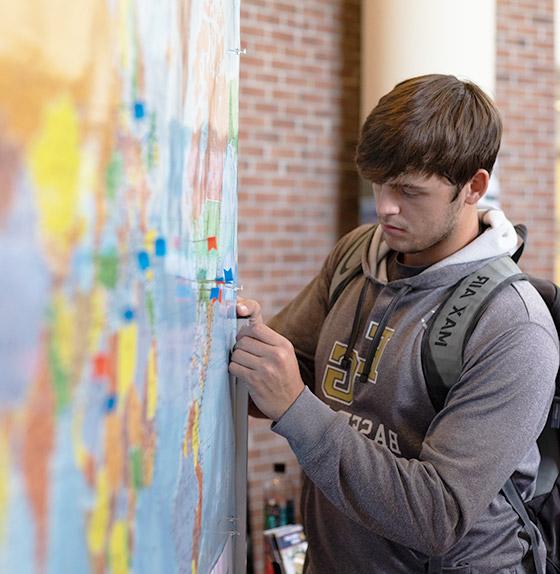 male student placing pin on map